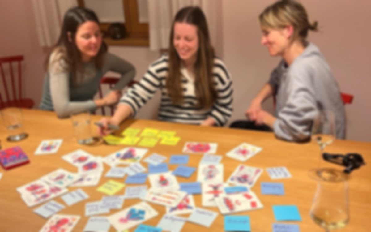 Drei Frauen an einem Holztisch entwickeln mit Bildkarten und Notizzetteln gemeinsam Ideen für ein Netzwerk